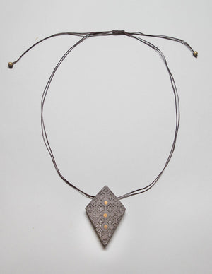 Yomo Studio rhombus dots necklace. Materials include: concrete, brass, metal beads, and wax string.
